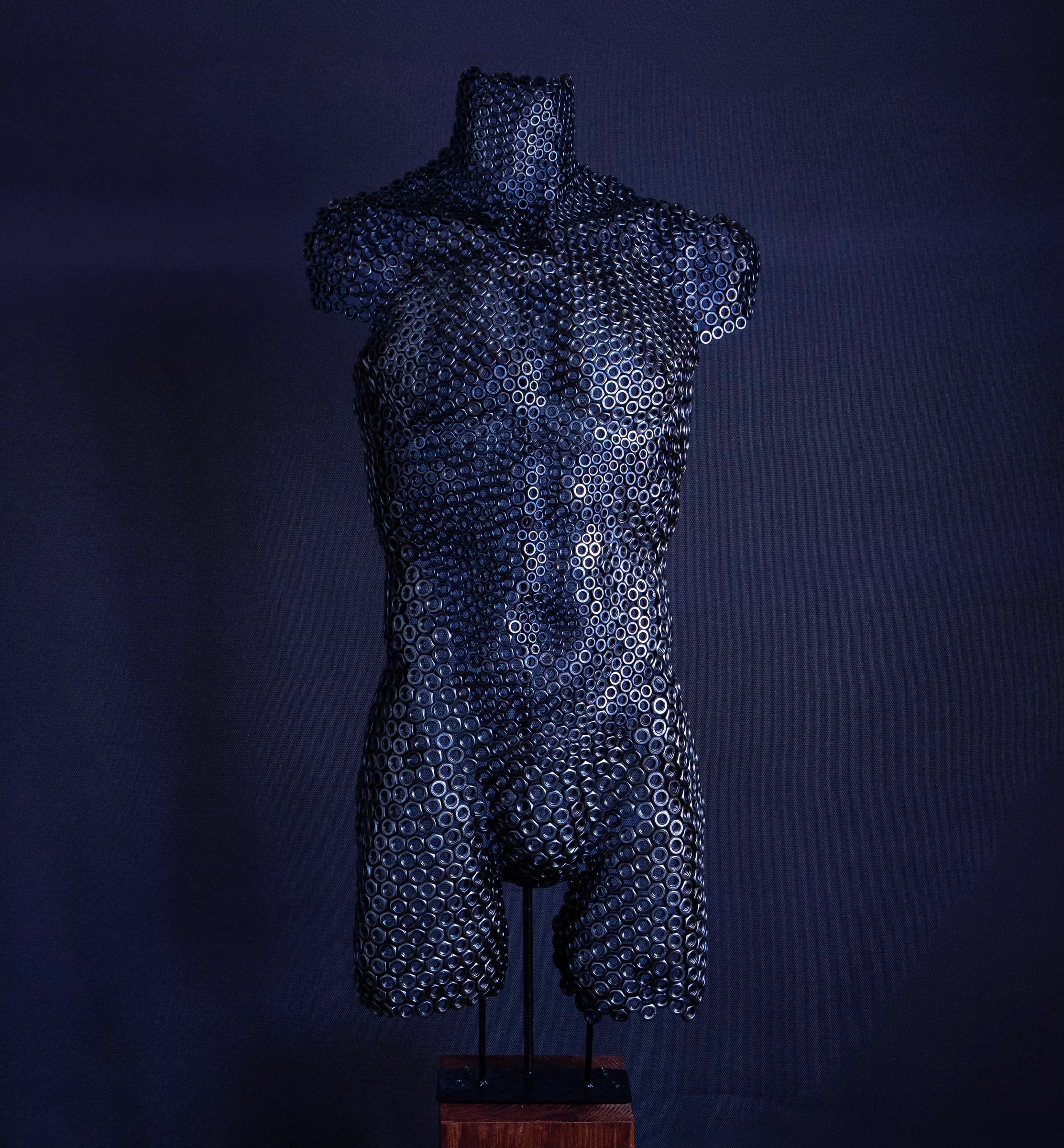 Forged Identity — mannelijke torso van zwarte stalen moeren op een houten sokkel